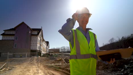 Wide-angle-extreme-closeup-of-woman-engineer-architect-walking-towards-camera-on-construction-site-and-looking-at-camera-and-smiling,-putting-pencil-behind-ear-and-giving-thumbs-up-sign