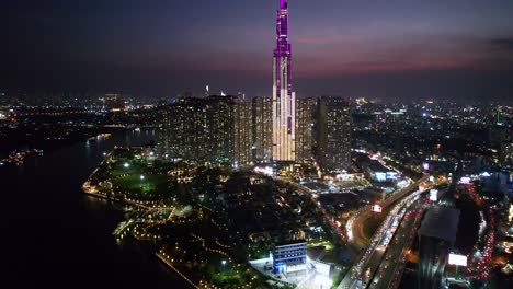 panorámica aérea amplia que revela el edificio emblemático 81 rodeado de bloques de apartamentos en saigón, vietnam por la noche