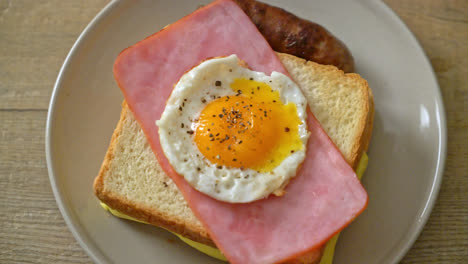 homemade bread toasted cheese topped ham and fried egg with pork sausage for breakfast