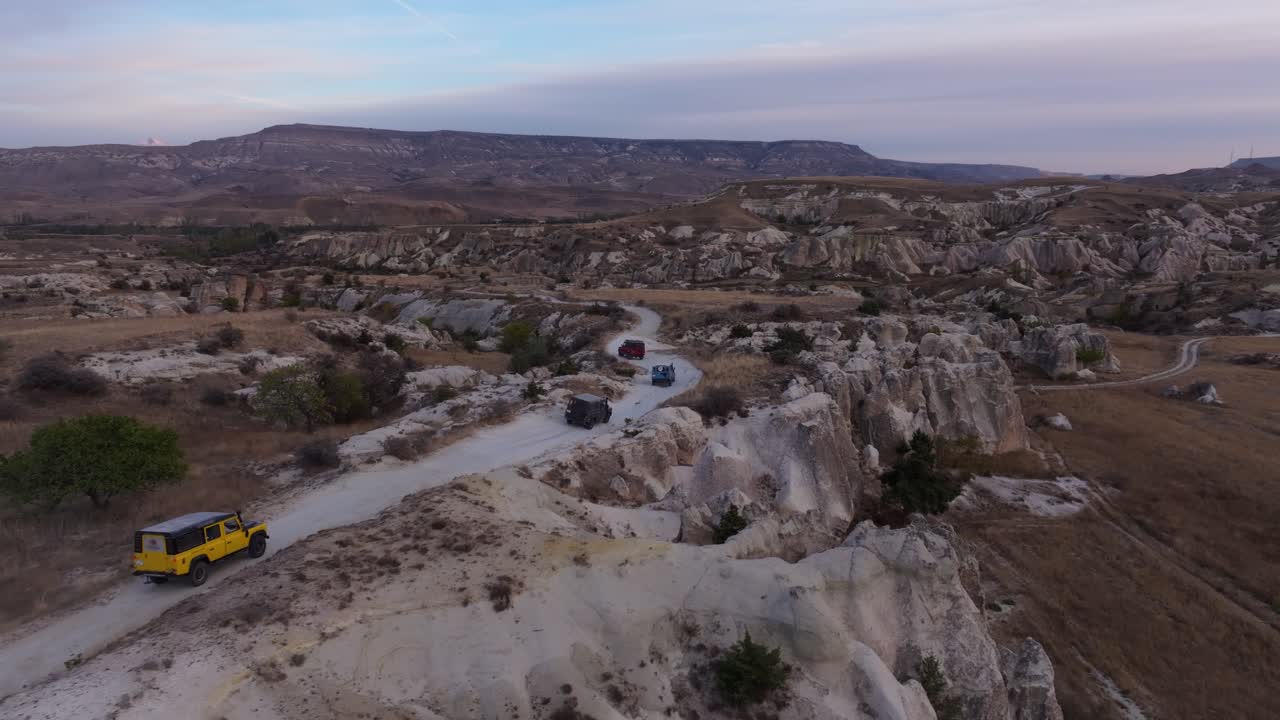 Vista aerea di veicoli fuoristrada che guidano nella valle rocciosa al tramonto