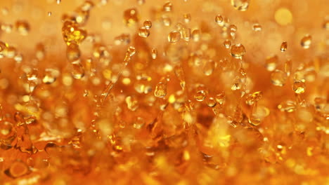 amber whisky splashing in slow motion - abstract golden energetically bouncing liquid makes droplets and splashes in macro
