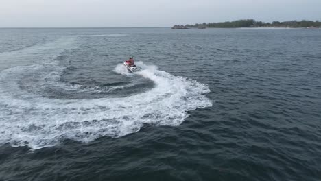 drone shot tracking jet ski with tourists having fun on exotic holiday