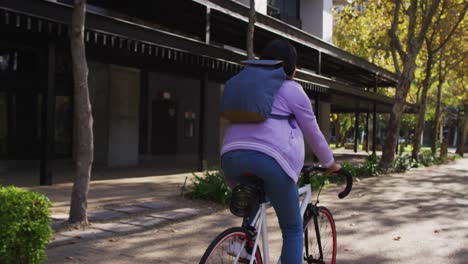 Rear-view-of-asian-woman-riding-bicycle-on-the-road