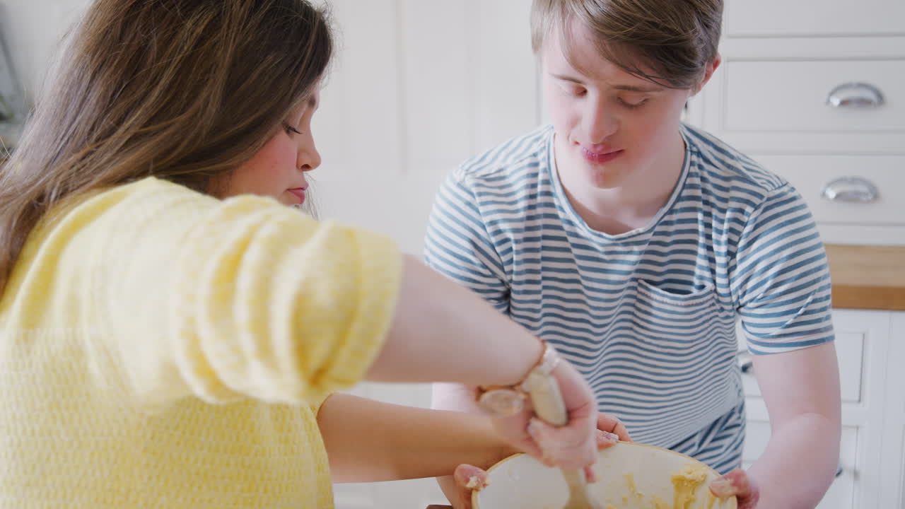 다운 증후군의 젊은 부부는 집에서 주방에서 케이크 레시피를 만들기 위해 재료를  ⁇ 고 있습니다.