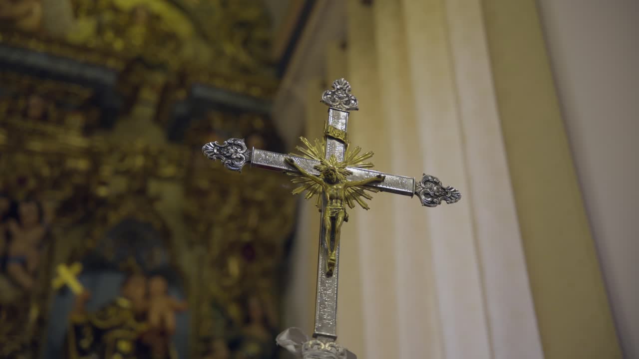 Detailní záběr zblízka zdobeného stříbrného a zlatého krucifixu s Ježíšem Kristem uvnitř historického kostela
