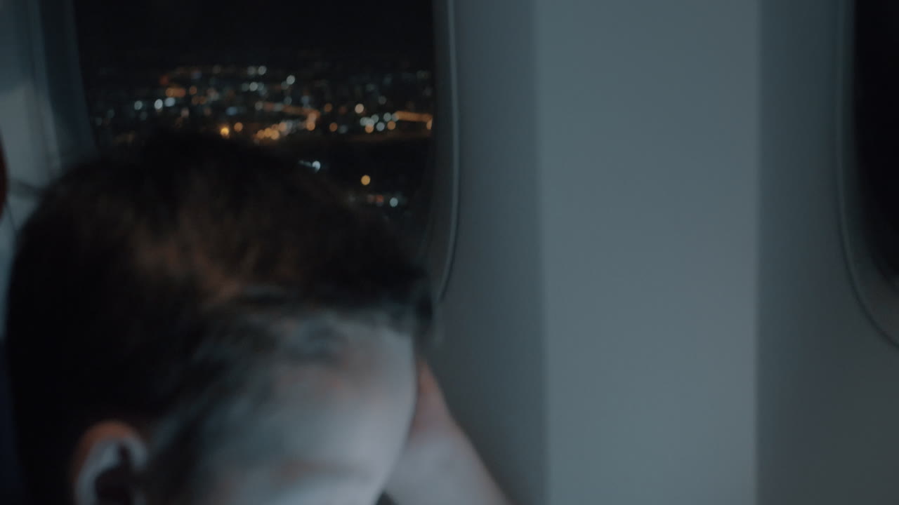 플레인 내부의 야간 도시 라이네이터와 태블릿 pc를 가진 소년