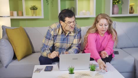 una pareja de ancianos maduros calculando facturas y recibos de gastos usando una computadora portátil en casa.