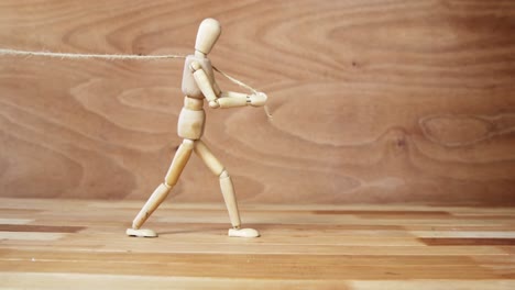 wooden figurine pulling a rope on wooden floor