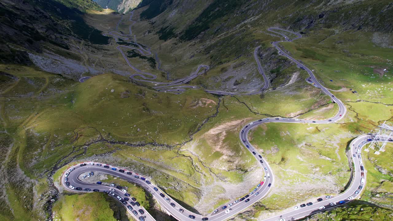 Top down bird's eye view of treacherous Transfagarasan Serpentine Road switchbacks covered in shadow of mountain ridges