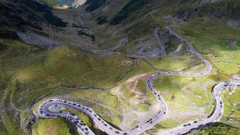 Top-down-bird's-eye-view-of-treacherous-Transfagarasan-Serpentine-Road-switchbacks-covered-in-shadow-of-mountain-ridges