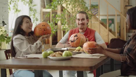 los amigos están mirando y hablando de sus calabazas de halloween pintadas