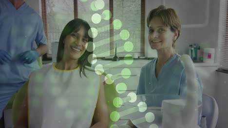 animation of dna strands over caucasian female doctor with biracial female patient in hospital