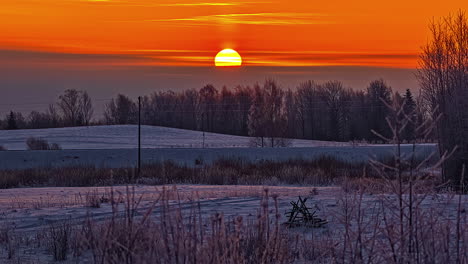 time-lapse of yellow sun rising in golden sky over snowy landscape at sunrise