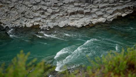 mirando hacia abajo a un arroyo cristalino que corre a través de un valle rocoso en islandia