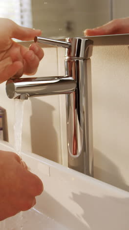 man washing his hands in bathroom sink