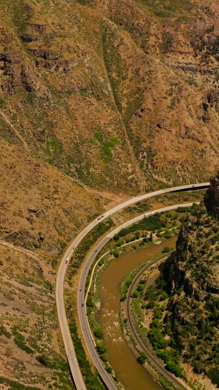 Scenic picture of mountainous area. Speed highways going along the narrow river between mountains. Aerial view. Vertical video