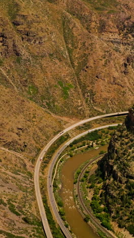 scenic picture of mountainous area. speed highways going along the narrow river between mountains. aerial view. vertical video