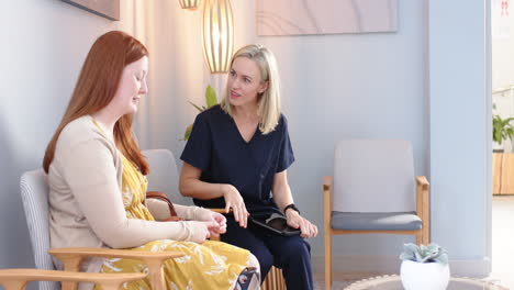 healthcare professional in scrubs talking with patient in waiting room, smiling, copy space