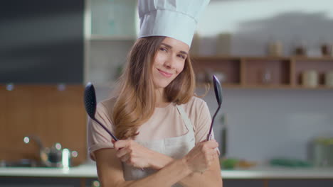 mujer posando con delantal y herramientas de cocina