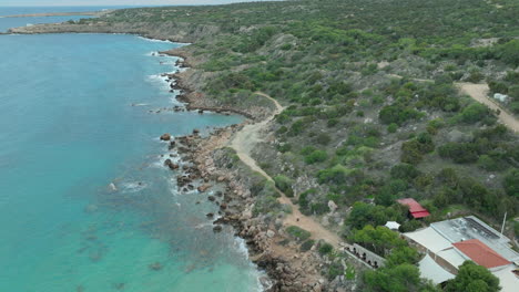 An-aerial-shot-of-Konnos-Beach-in-Ayia-Napa,-Cyprus,-highlights-a-secluded-cove-with-golden-sands,-clear-blue-waters,-and-surrounding-greenery,-a-perfect-spot-for-relaxation-and-swimming