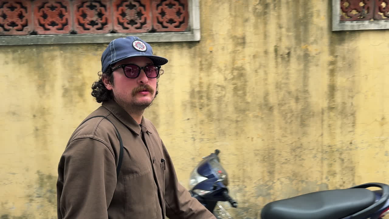 Hanoi Eski Mahallesi'nde bir duvar boyunca yürüyen ve sigara içen adam.