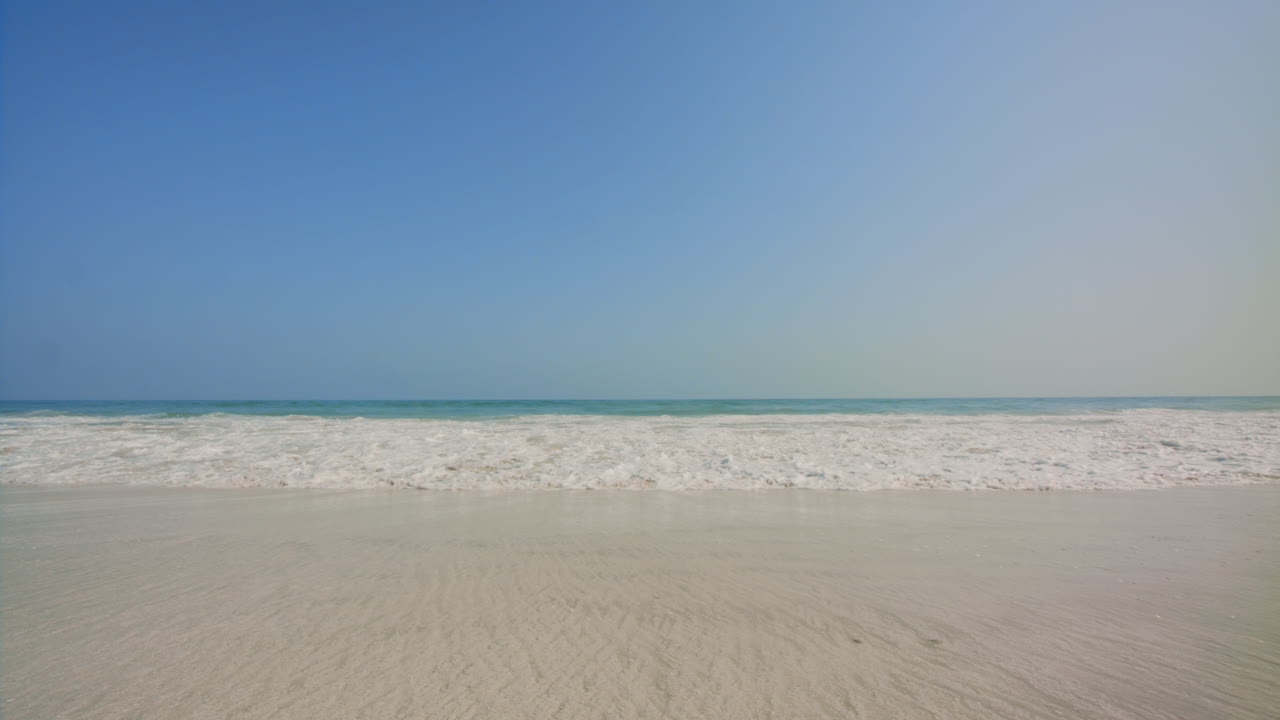 Approaching blue sea, Ocean beach waves then water slides under the camera. 4k footage