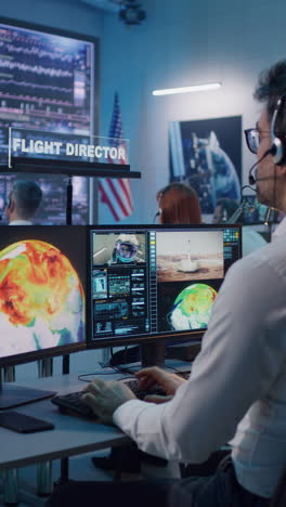 vertical shot of operators and flight director using computers then applauding and shaking hands after successful launch of rocket