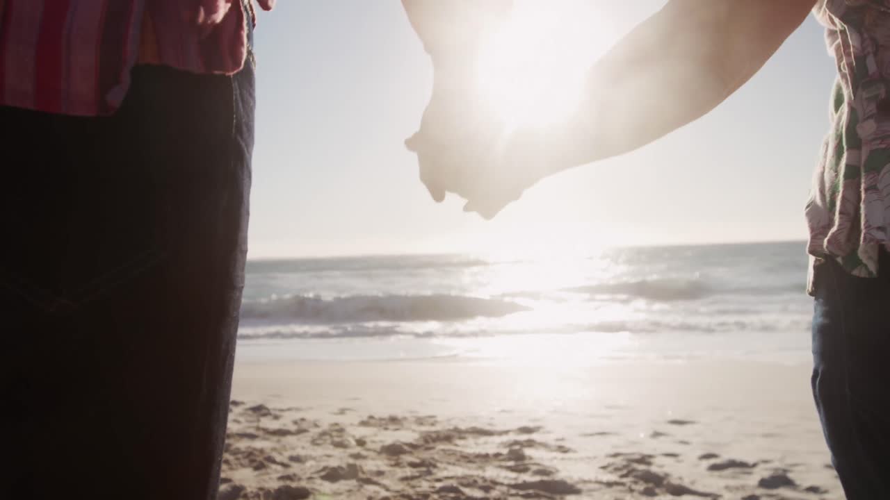 시니어 커플이 해변에서 손을 잡고 있다