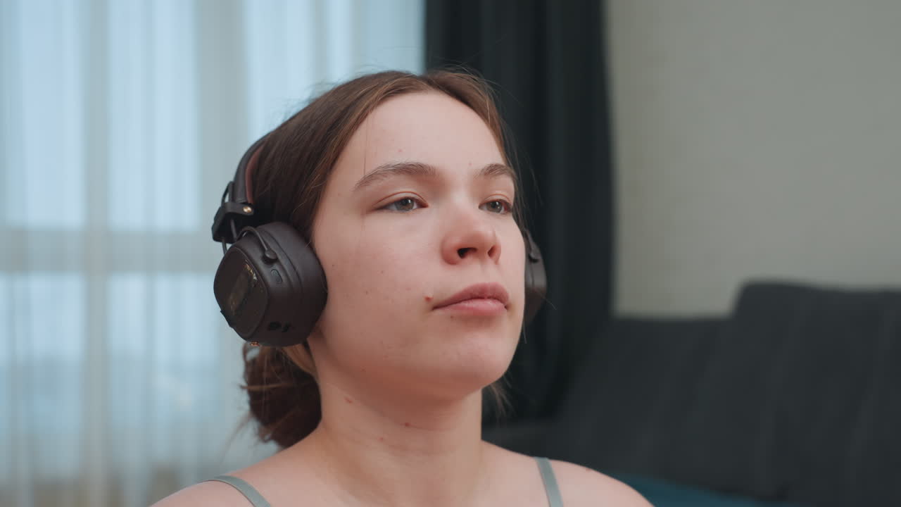 Zwangere Kaukasische vrouw luistert met koptelefoon in rustige woonkamer, close-up profiel toont peinzende blik en zacht omgevingslicht, perfect voor prenatale reflectie en audiomeditatie