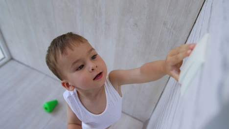 excited caucasian toddler boy presses on the light switch. happy turns on the off the light. top view. close up.