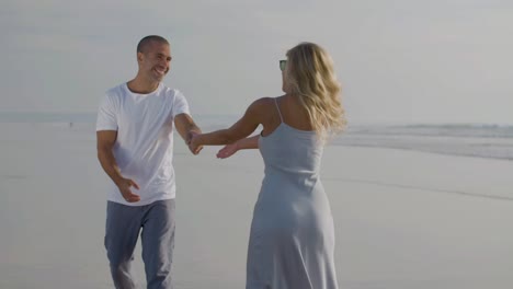 una feliz pareja caucásica divirtiéndose mientras caminan por la costa.