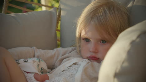 young adorable girl daydreaming in rocking chair outside in summer, close face portrait