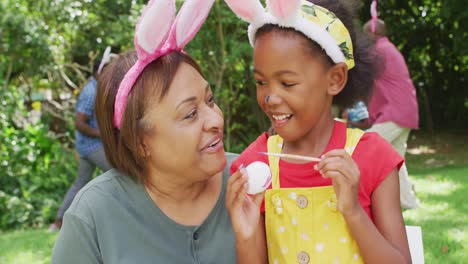 Animación-De-Feliz-Abuela-Y-Nieta-Afroamericana-Pintando-Huevos-De-Pascua-En-El-Jardín