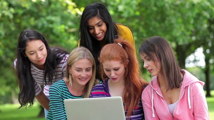 Female students looking at the laptop together outside