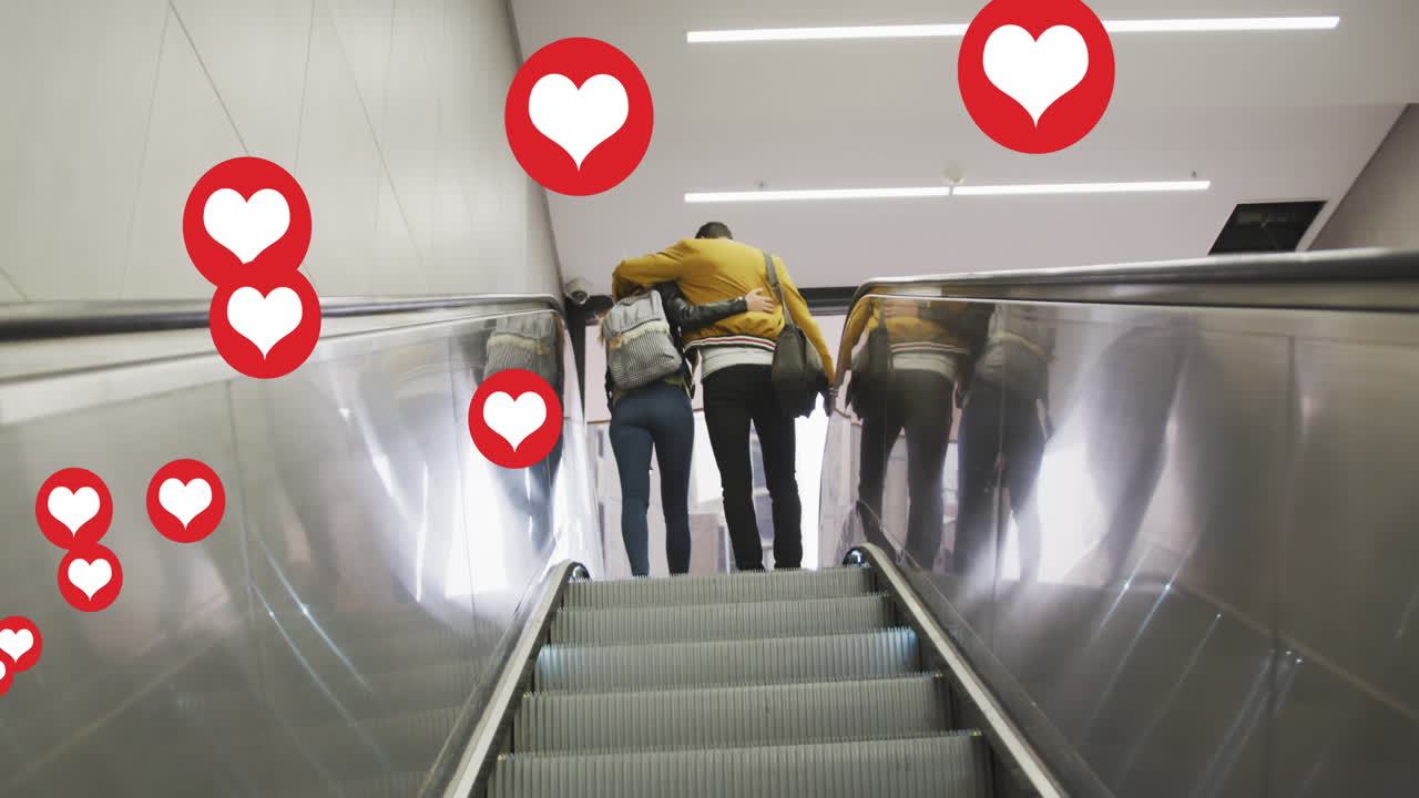 Animación de iconos de corazón flotando sobre pareja abrazándose en escaleras mecánicas