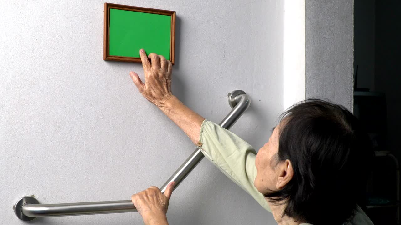 벽에 있는 기억의 사진을 보고 있는 노인 여성 (녹색 화면)