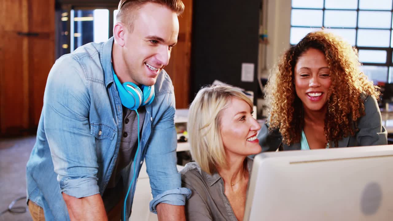 Businesswoman interacting with coworkers while working on computer