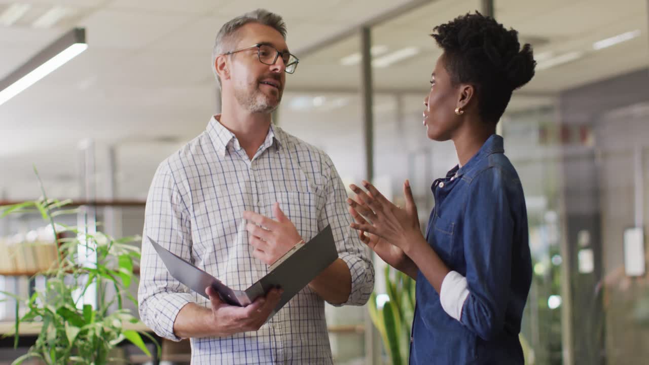 Video of happy diverse businessman and businesswoman talking about project