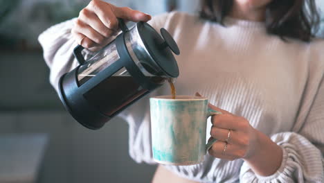 a woman pouring herself coffee from a plunger