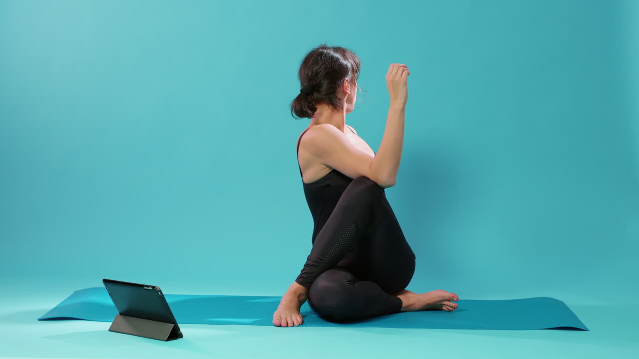 Fit adult following pilates lesson on tablet to stretch body