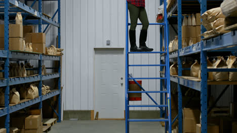 Side-view-of-caucasian-female-worker-checking-packed-goods-in-warehouse-4k