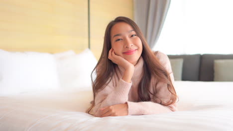 close-up of an attractive young woman lying on her stomach on a comfortable bed feeling very pleased with herself