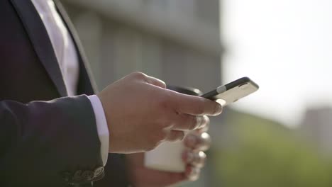 cropped shot of man texting by smartphone outdoor