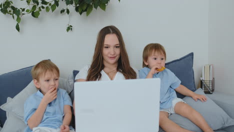 hermosa madre joven y dos niños pequeños niños están mirando la pantalla del portátil fotos de la familia. y hacen compras en línea. llame a la abuela a través de video chat