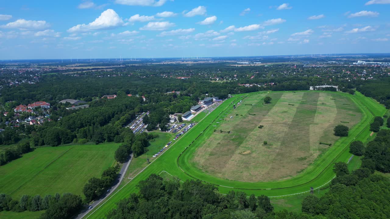 Jockeys on racehorses on horse racing track, showcasing the vibrant green turf, stands filled with spectator landscape beyond. Fabulous aerial view flight panorama overview drone
