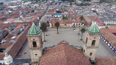 Drone video captures Zipaquira's historic main plaza, showcasing colonial architecture and surrounding town. Overhead perspective highlights red-tiled roofs and urban layout