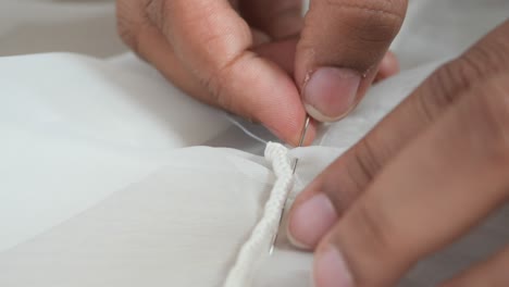 close-up of a hand sewing fabric with a needle and thread