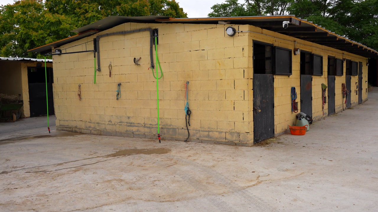 Equestrian stables with upper doors open. Panning left shot