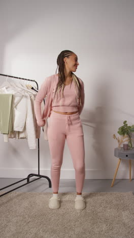 vertical pov video of female social media influencer producing user generated content in studio modelling a variety of fashion outfits shot in real time