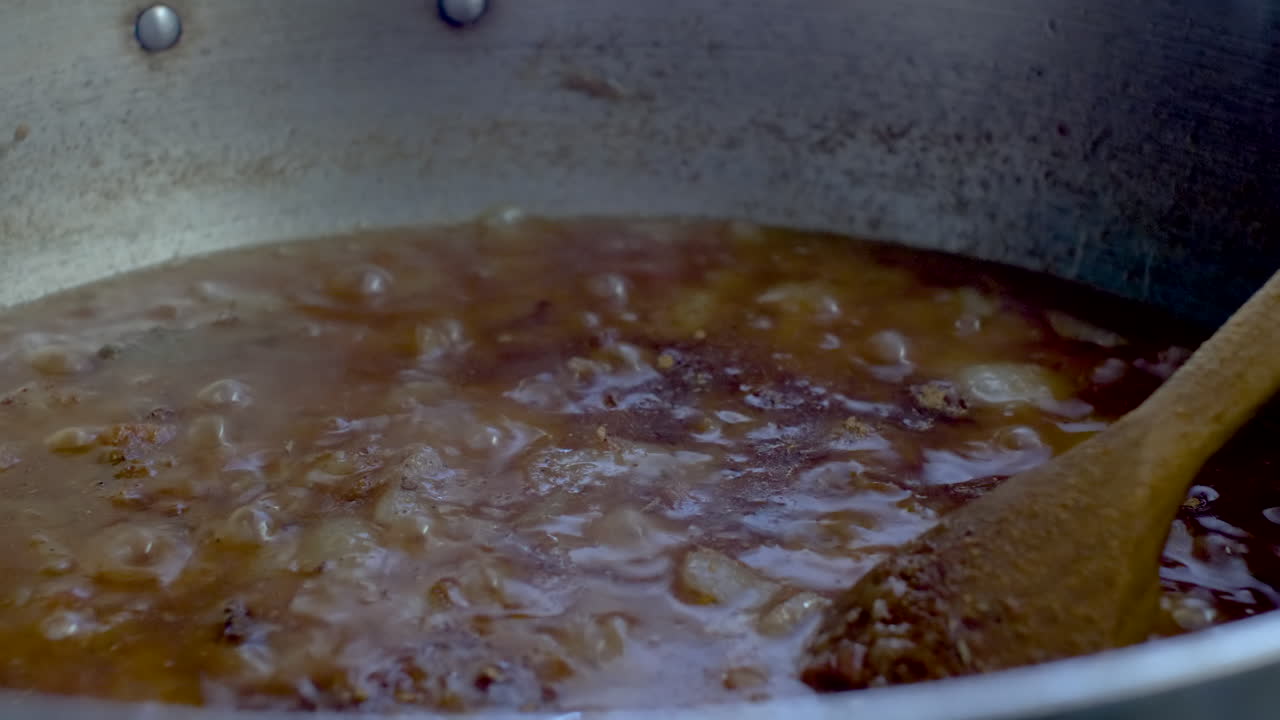 Spezie in polvere aggiunte a una salsa curry che sobbolle in pentola.